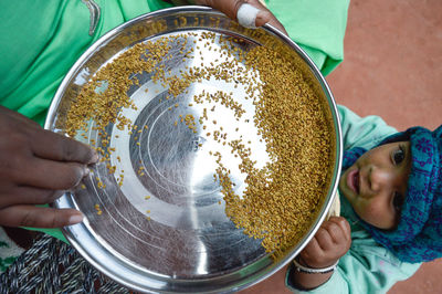 Daughter standing by mother holding food in plate