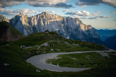 Empty curved mountain road under dramatic cloudy sky