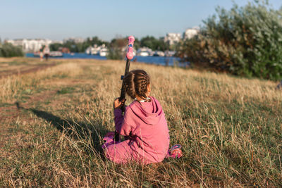 Rear view of woman sitting on field