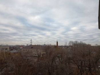 Bare trees and buildings against sky