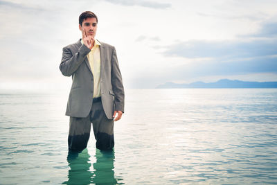 Portrait of young man standing in sea against sky