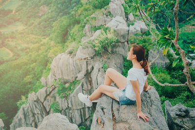 Rear view of mid adult woman looking at view while sitting on mountain