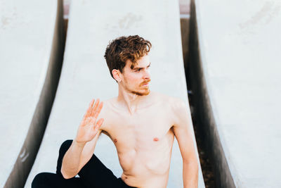 Shirtless man exercising while sitting outdoors