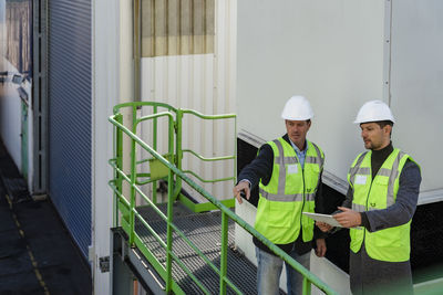 Engineer discussing with colleague gesturing at recycling plant