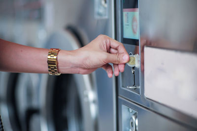 Cropped hand of woman inserts the coin into the vending machine