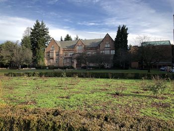 Plants growing on old building by trees against sky