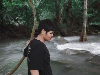 Side view of man standing by river in forest