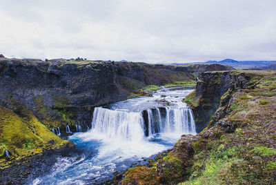 Scenic view of waterfall against sky