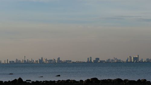 Sea by city buildings against sky