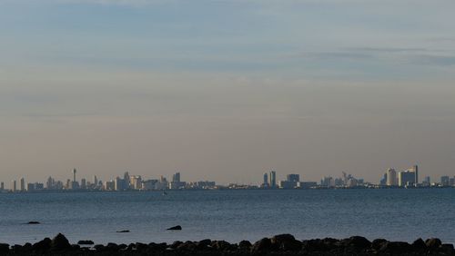 Sea by city buildings against sky