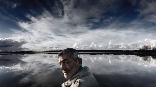 Side view portrait of man standing against lake with reflection