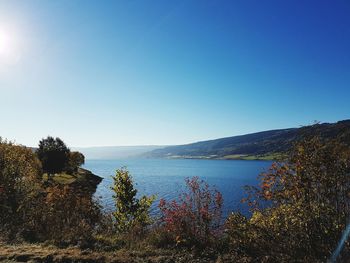 View of calm lake against clear blue sky