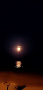 Close-up of illuminated sea against sky at night