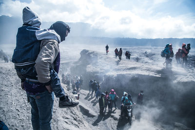 People on mountain against sky during foggy weather