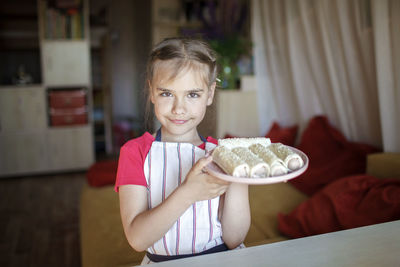 Portrait of girl holding camera at home