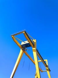 Low angle view of crane against clear blue sky