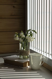 Flower vase on table against window