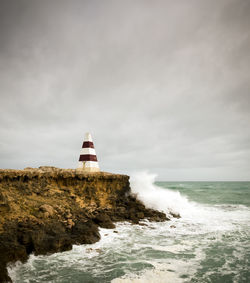 Lighthouse by sea against sky