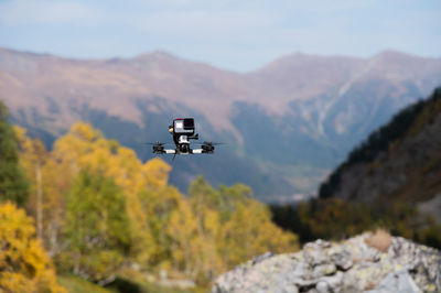 Fpv drone hovering in the air, filming a forest in the mountains with an action camera attached to