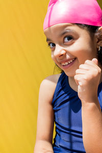 Portrait of young woman against yellow background