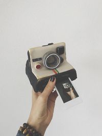 Close-up of woman photographing camera against white background