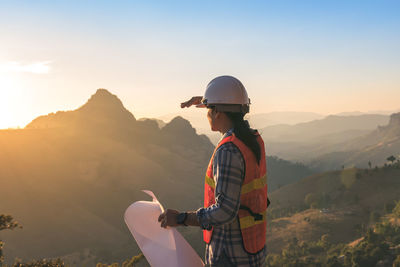 Man standing on mountain against sky during sunset