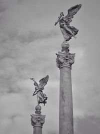 Low angle view of angel statue against cloudy sky