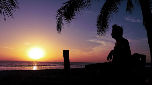 Silhouette people looking at sea against sky during sunset