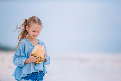 Side view of young woman standing against sea
