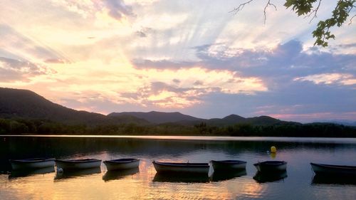 Boats moored in lake against sky during sunset