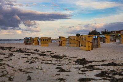 Hooded chairs on beach against sky