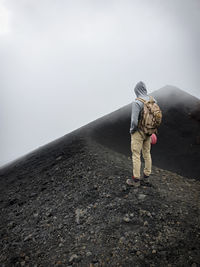 A man contemplates the path on the slopes of a volcano