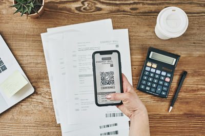 Woman scanning qr code from bill to make payment using payment app on smartphone. paying bills