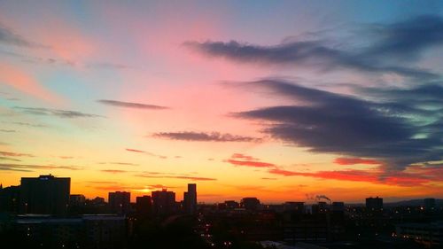 Silhouette buildings against dramatic sky during sunset