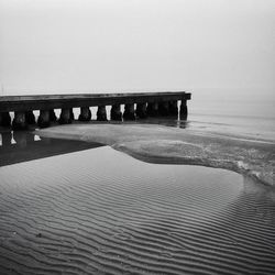 Pier over beach against sky