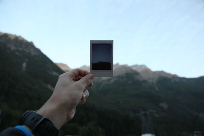 Close-up of hand holding mountain against sky