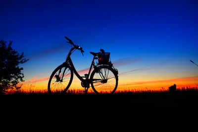 Silhouette bicycle on field against sky during sunset