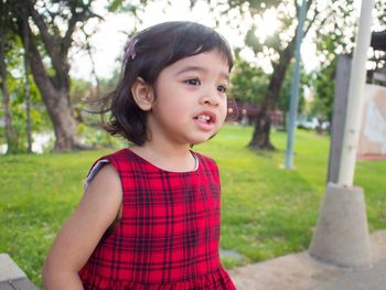 Cute smiling girl looking away while standing at park