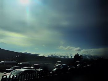 Cars on road against cloudy sky