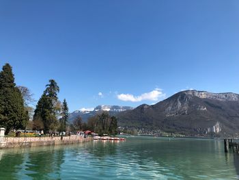 Scenic view of lake and mountains against clear blue sky