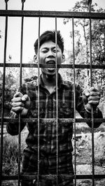 Portrait of young man screaming by fence