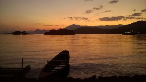 Boats moored in sea at sunset