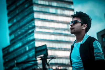 Young man looking away while standing in city