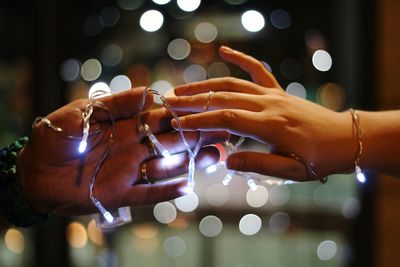 Midsection of woman holding illuminated lights at night