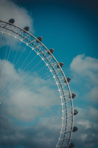 Low angle view of ferris wheel against cloudy sky