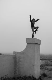 Low angle view of man jumping against clear sky