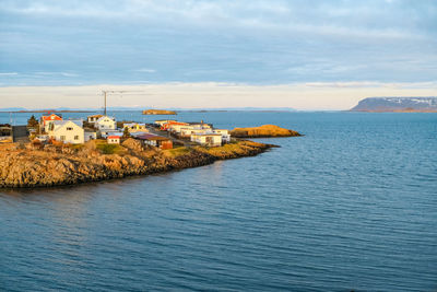 Scenic view of sea by buildings against sky