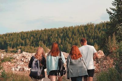 Rear view of people standing on land against trees