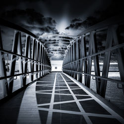 Footbridge over footpath amidst buildings against sky