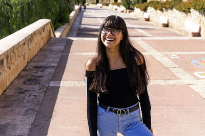 Portrait of smiling young woman wearing sunglasses standing outdoors